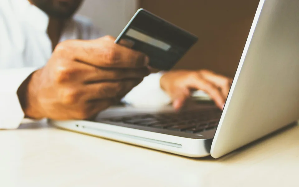 Customer making an online purchase with a payment card and laptop.